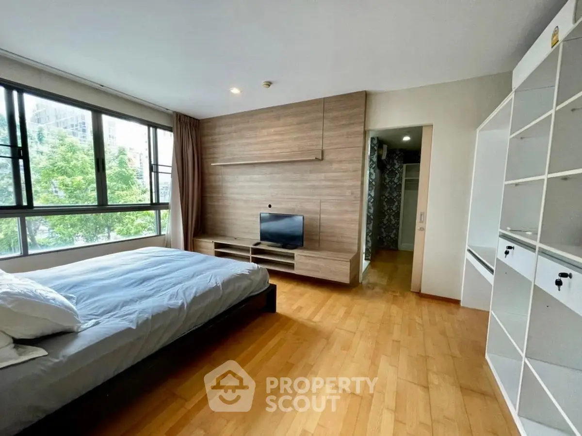 Spacious bedroom with large windows and modern furnishings in a stylish apartment.
