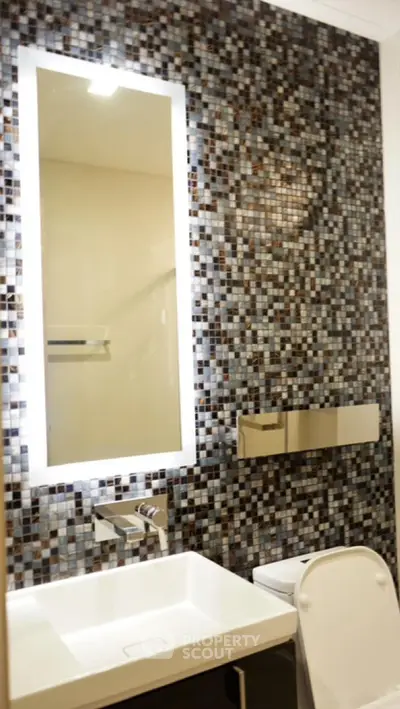 Modern bathroom with mosaic tile wall and illuminated mirror
