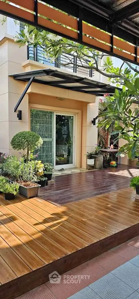 Charming garden patio with wooden deck and lush greenery in modern home exterior.
