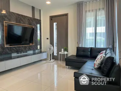 Spacious living room with glossy tiled flooring, elegant black leather sofa, and a mounted flat-screen TV against a stylish marble wall.