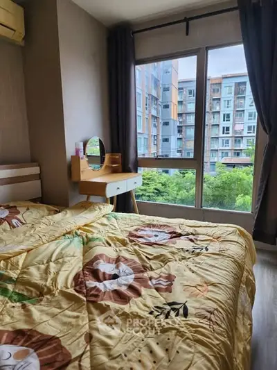 Cozy bedroom with large window offering a lush green view in modern apartment.