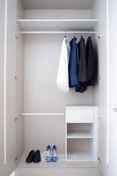 Spacious modern closet with hanging clothes and shoes, perfect for organized living.