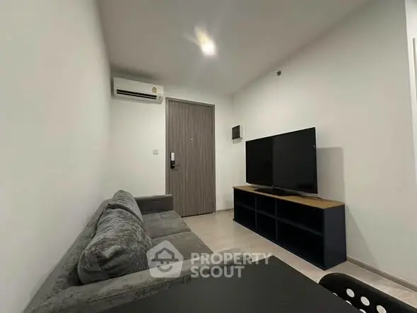 Modern living room with sleek furniture and large TV in a cozy apartment setting.