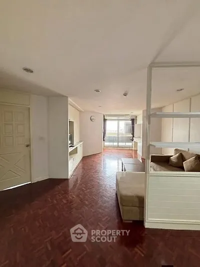 Spacious living room with elegant parquet flooring and cozy seating area, featuring natural light from large windows.