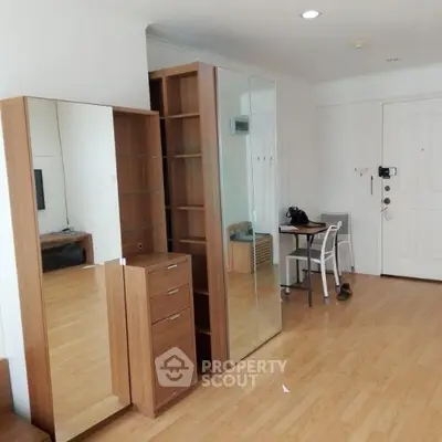 Spacious living area with wooden flooring and modern furniture in a bright apartment.