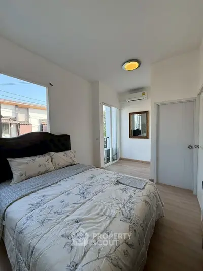 Bright and cozy bedroom with modern decor and large window for natural light.