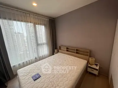 Modern bedroom with large window and city view, featuring a comfortable bed and stylish decor.