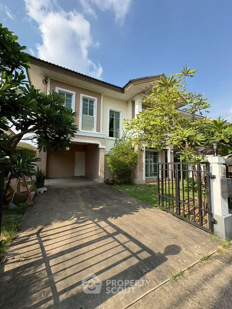 Charming two-story house with lush garden and driveway in a serene neighborhood.
