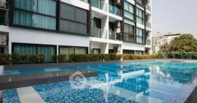 Modern apartment building with luxurious outdoor swimming pool and lush greenery.