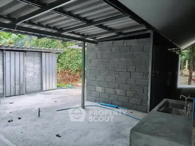 Spacious outdoor area with unfinished concrete structure and metal roofing, ideal for customization.