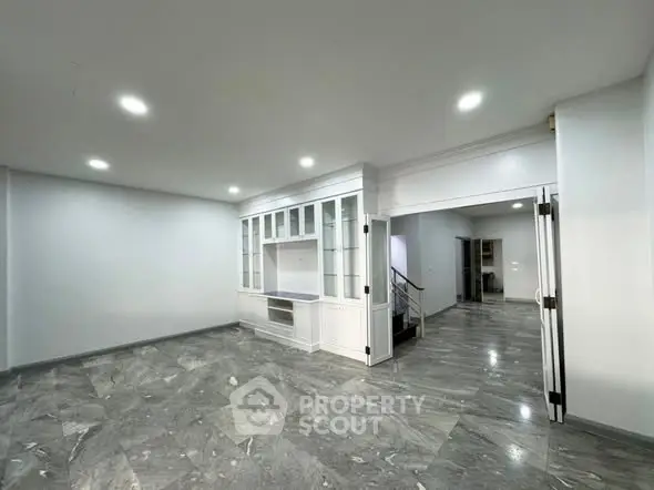 Spacious modern living room with elegant marble flooring and built-in cabinetry.