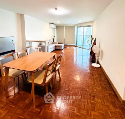 Spacious living room with wooden flooring and modern furniture in a bright apartment.