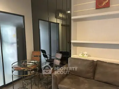 Modern living room with stylish furniture and glass dining table in a cozy apartment setting.