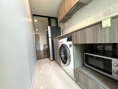 Modern kitchen with washing machine and microwave in sleek apartment
