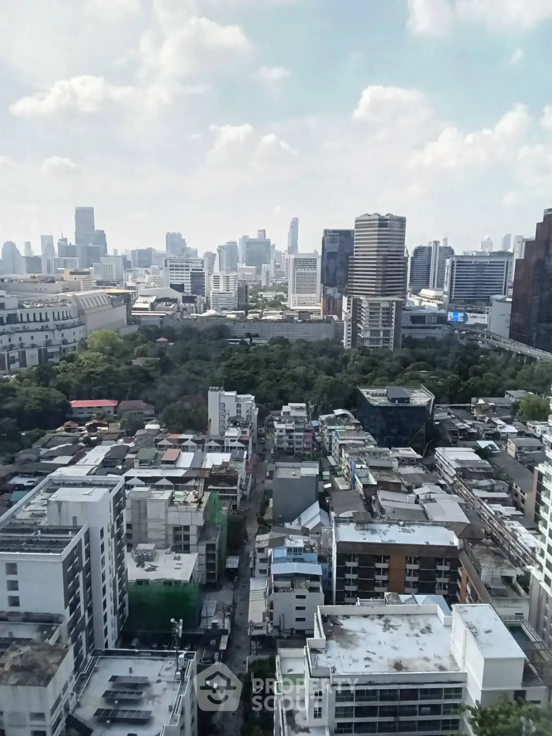 Stunning cityscape view from high-rise building showcasing urban skyline and lush greenery.
