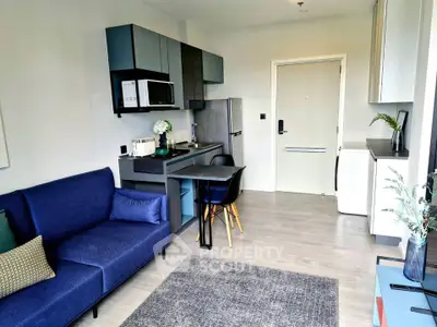 Modern open-layout living room with kitchenette, featuring sleek cabinetry and cozy seating.