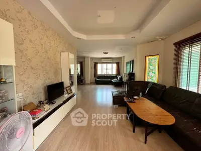 Spacious living room with modern decor and ample natural light, featuring a cozy seating area and stylish wooden flooring.
