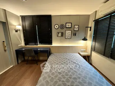 Modern bedroom with stylish decor and workspace, featuring wooden flooring and elegant lighting.