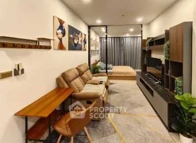 Modern open-plan living room with cozy seating and stylish decor leading to a bedroom area.