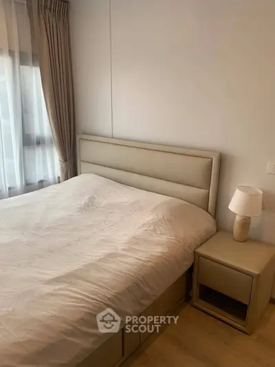 Cozy bedroom with modern decor and natural light, featuring a comfortable bed and stylish nightstand.