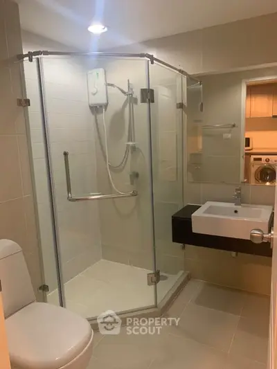 Modern bathroom with glass shower enclosure and sleek fixtures in a contemporary apartment.