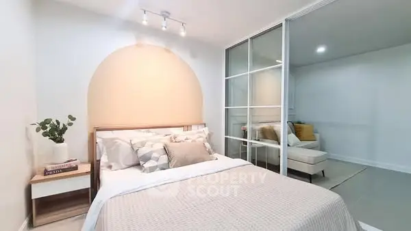 Modern bedroom with stylish decor and sliding glass doors to cozy sitting area.