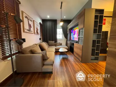 Modern living room with stylish decor and wooden flooring, featuring a cozy sofa and entertainment unit.