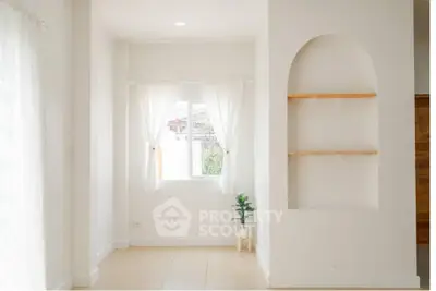 Bright minimalist room with arched wall niche and window view.