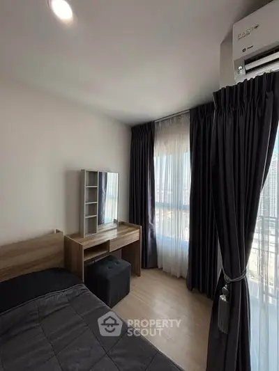 Modern bedroom with sleek furniture and large window offering city views.