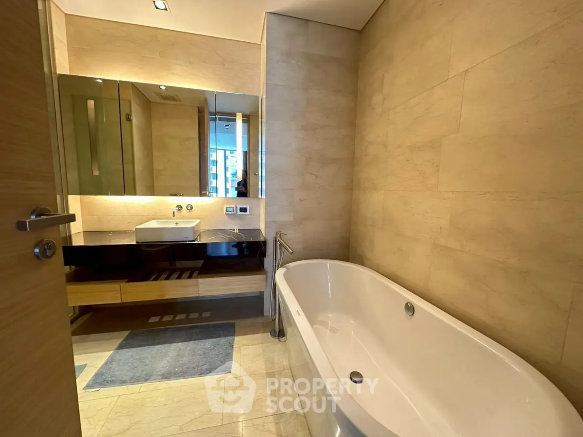 Luxurious bathroom with elegant bathtub and modern vanity in upscale apartment.