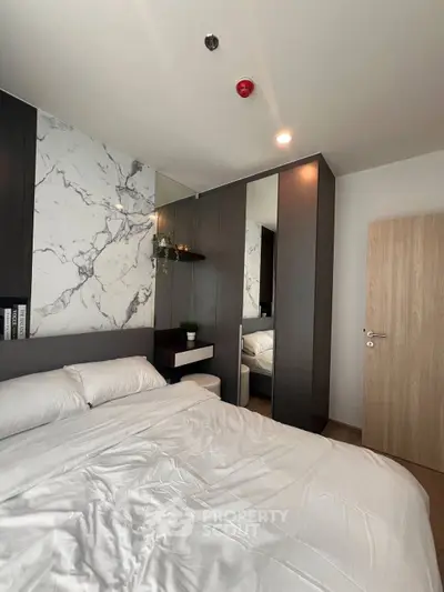 Modern bedroom with marble accent wall and sleek mirrored wardrobe