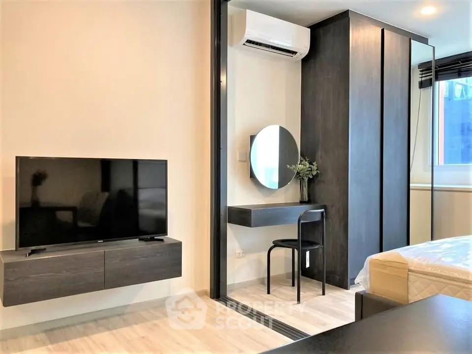 Modern bedroom with sleek furniture, wall-mounted TV, and stylish vanity area.