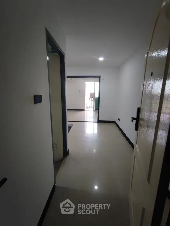 Spacious apartment entrance with glossy floors and bright lighting