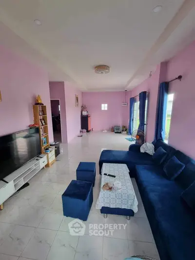 Spacious living room with modern blue sofa and entertainment center in a bright, airy home.