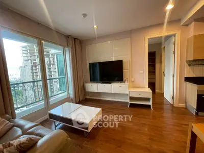 Modern living room with large TV, elegant furniture, and balcony view in upscale apartment.