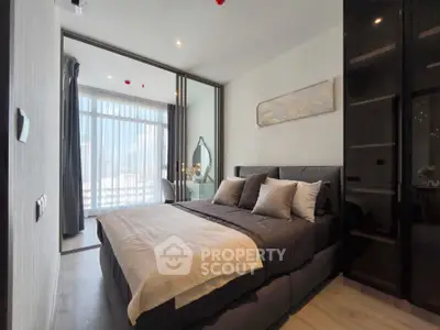 Modern bedroom with stylish decor and large window offering natural light.