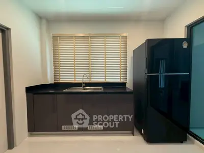 Modern kitchen with sleek black cabinets and large refrigerator