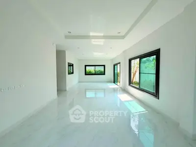 Spacious modern living room with large windows and glossy white flooring.