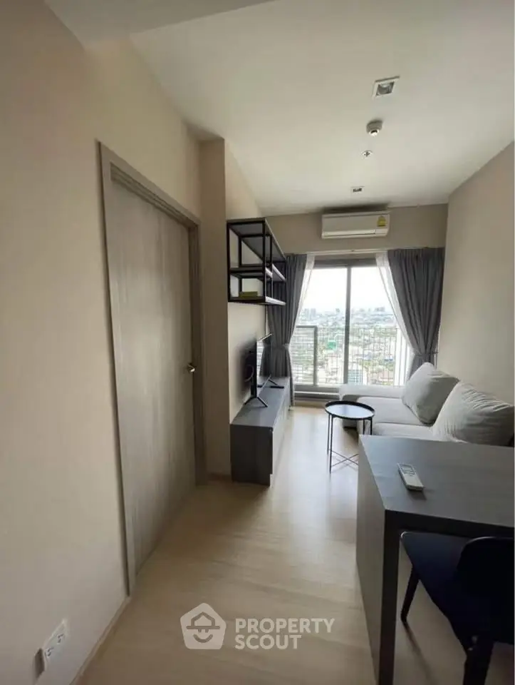 Modern living room with large window and stylish furniture in a high-rise apartment.