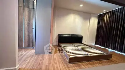 Spacious modern bedroom with sleek wooden flooring and minimalist bed frame.