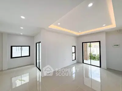 Spacious modern living room with large windows and sleek tile flooring.