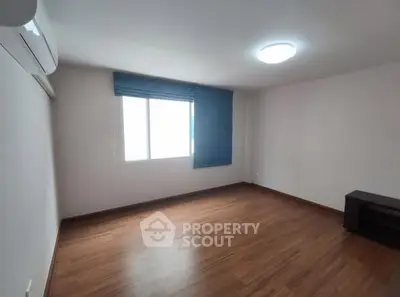 Spacious empty room with wooden flooring and large window