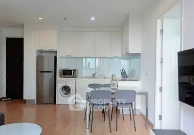 Modern kitchen with dining area, featuring washing machine and sleek appliances.