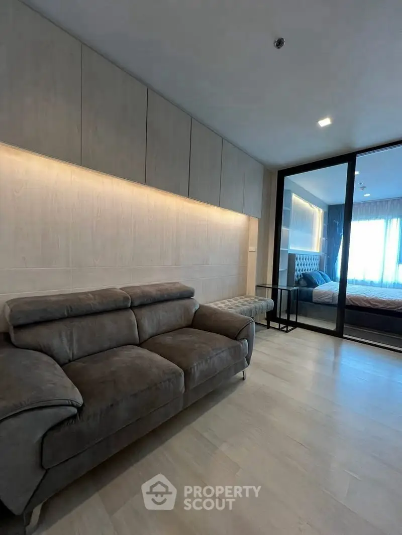 Modern living room with sleek design and cozy sofa adjacent to a stylish bedroom.