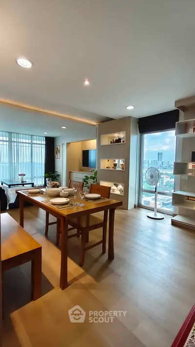 Spacious modern living room with dining area and city view, featuring elegant wooden furniture.