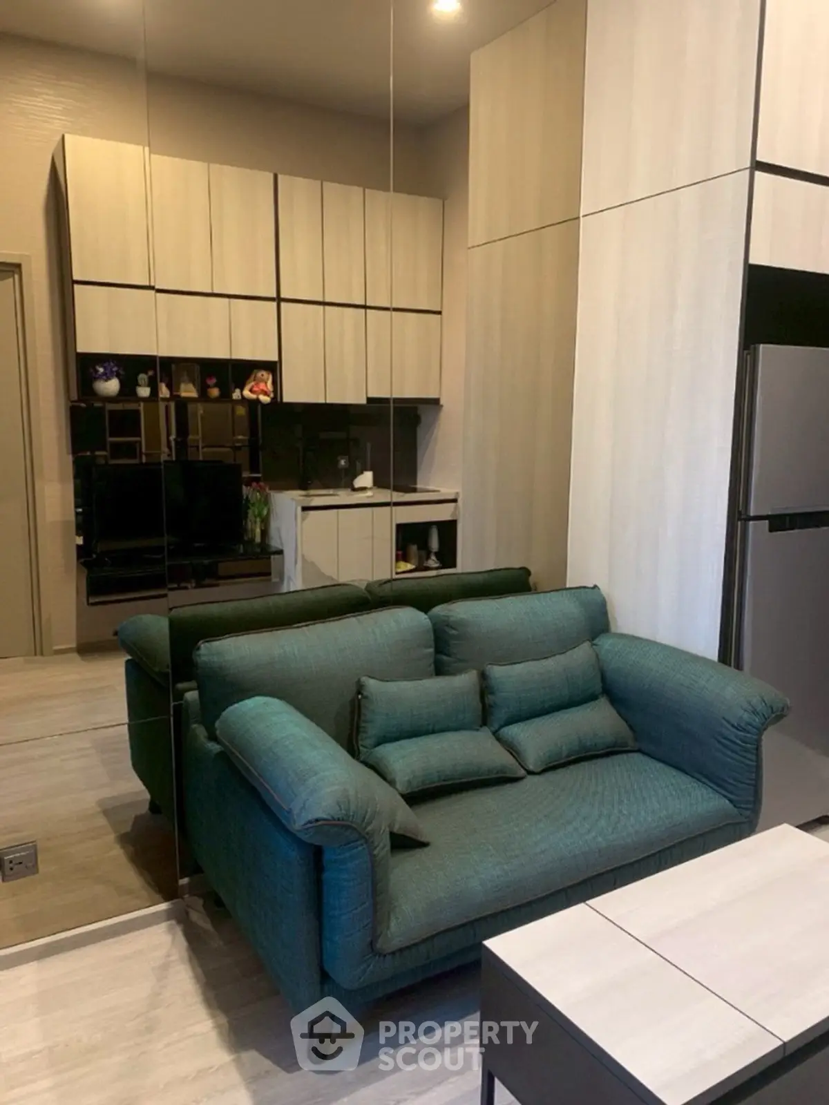 Modern living room with teal sofa and sleek kitchen design