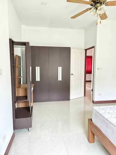 Spacious bedroom with modern wardrobe and ceiling fan in a bright, airy apartment.