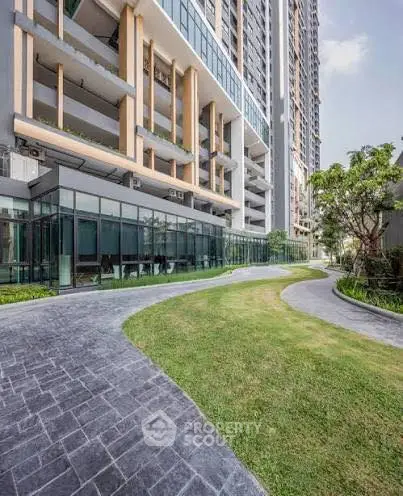 Modern high-rise building with landscaped garden and glass facade