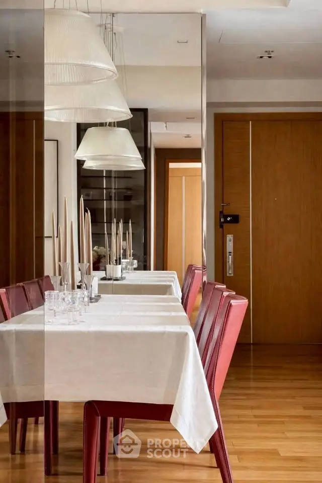 Elegant dining area with red chairs and modern lighting in a stylish apartment.