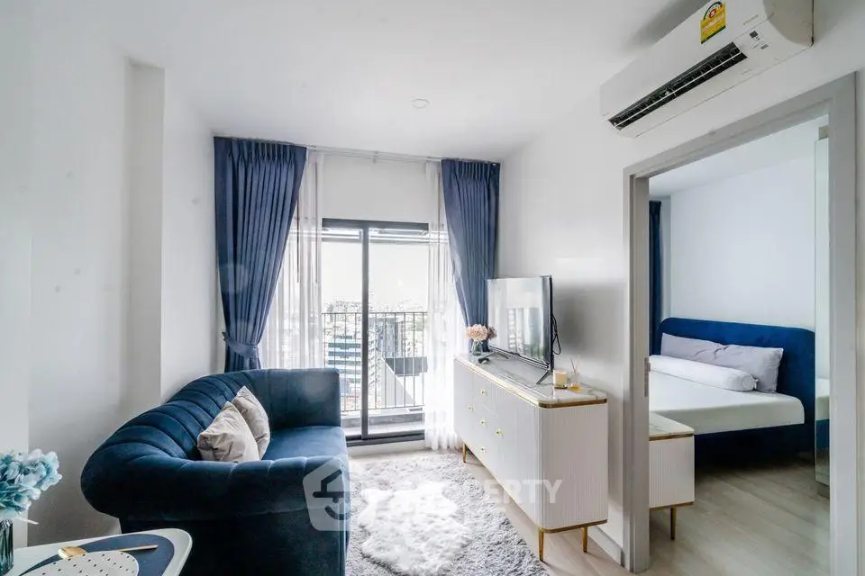 Modern living room with blue sofa, TV, and balcony view in a stylish apartment.